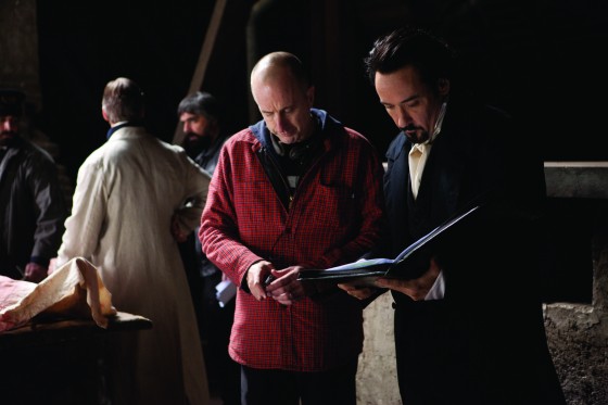 (Left to right.)  Director James McTeigue discusses a scene with star John Cusack on the set of Relativity Media's upcoming release The Raven.  Photo Credit: Larry Horricks © 2011 Incentive Film Productions, LLC. All rights reserved.